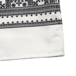 Detailed view of bohemian geometric embroidery on white cotton fabric dress