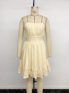 Detail of yellow mini dress featuring smocked waist and ruffled hem with crinkled texture