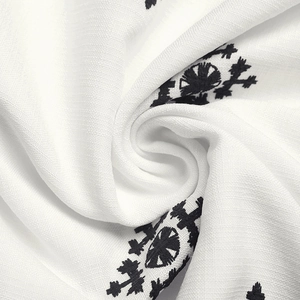 Macro shot of ethnic pattern embroidery on white breathable cotton fabric texture