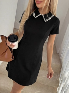Detailed view of hand-sewn white pearls on the elegant black dress Peter Pan collar