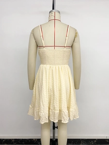 Detail of cream smocked back strap dress with textured fabric and ruffled hemline