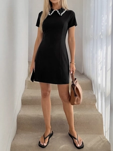 Detail view of the beaded white pearl collar design on this black short sleeve A-line dress