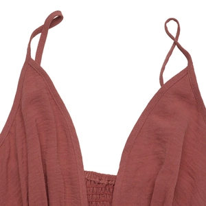 Detail view of brick red summer dress with deep V-neck, smocked bodice and pleated fabric
