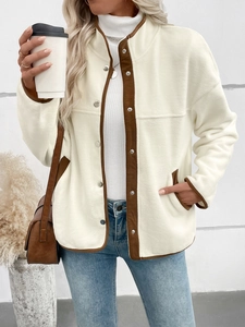Détail de la veste en polaire crème avec bordure marron et boutons-pression argentés