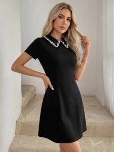 Close-up of elegant pearl-embellished Peter Pan collar on a black short sleeve A-line dress