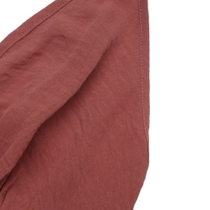 Detail shot of terracotta cotton linen fabric featuring precise double stitching on the hem