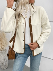 Détail de la veste en polaire contrastée avec boutons-pression et liseré marron