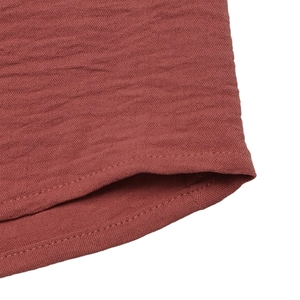 Detail view of brick red seersucker fabric featuring textured ripple folds and double stitching