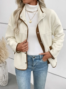 Détail d'une veste en polaire crème avec bordure marron et boutons-pression en argent