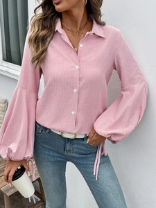 Détail de chemise à rayures rouges avec manches lanternes et poignets noués réglables