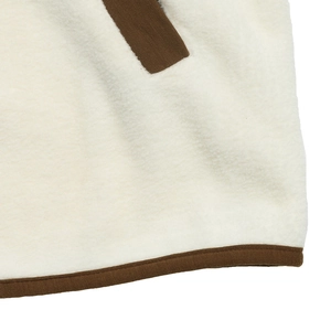 Détail de la texture polaire crème avec bordure cousue marron contrastée sur la veste