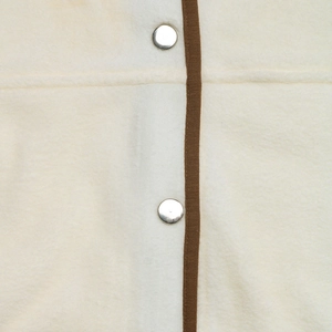 Détail du tissu polaire avec texture douce et boutons-pression argentés polis