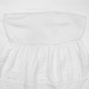 Detail of white smocked tube top featuring intricate eyelet lace embroidery and elastic texture