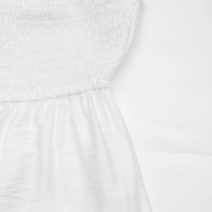 Close-up of smocking texture and lace stitching on white summer crop top fabric