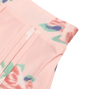 Détail de l'imprimé floral rose montrant les plis précis et la ceinture large du vêtement