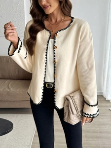 Detail of cream fleece cardigan featuring black contrast stitching and large brown buttons