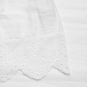 Detailed close-up of white eyelet lace embroidery on a slim fit cropped summer top