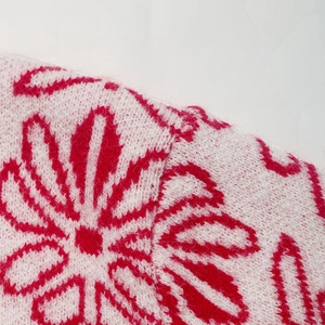 Close-up of pink Fair Isle knit sweater with red jacquard flower pattern and soft texture