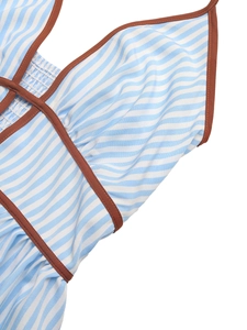 Detail of blue and white striped halter dress with brown piping and textured fabric