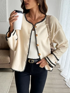 Detail of cream fleece cardigan with black contrast stitching and tortoiseshell buttons