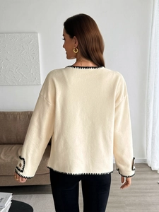Detail view of the beige knit jacket back with black crochet edges and decorative buttons