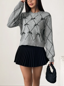Detail of grey knitted sweater featuring black diamond patterns and small bow accents