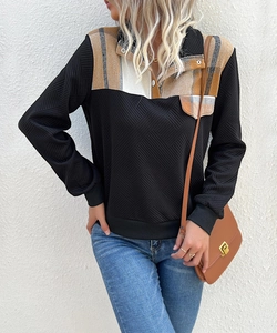 Detailed close-up of collar buttons and plaid patchwork on black casual sweatshirt