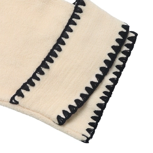 Detailed close-up of beige fleece fabric with black contrast decorative stitching