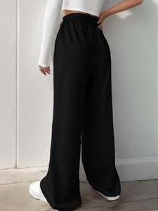 Detail view of black high waist wide leg pants with elastic V-waistband on female model