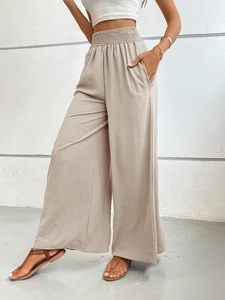 Close-up of smocked elastic high waist and pocket detail on khaki wide-leg trousers