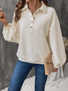 Close-up of white waffle texture fabric on long sleeve polo sweatshirt with brown buttons