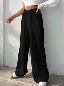 Close-up of high-waist elastic V-shape waistband on flowing black wide-leg trousers