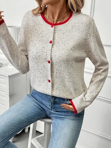 Close-up of beige knit cardigan featuring red heart buttons and contrasting trim details