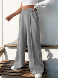 Detail view of the crossover V-shaped elastic waistband and seam on grey wide-leg pants