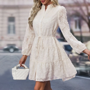 Close-up of white dress showing intricate 3D feather jacquard texture and layered hemline
