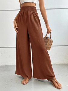 Detail of high waisted brown wide leg trousers with elastic ruched waistband and linen texture