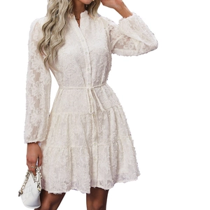 Detail of white lace dress featuring high neck, button front, and layered ruffle skirt