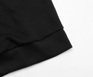 Close-up of black hoodie sleeve with 3D geometric texture and ribbed knit cuffs