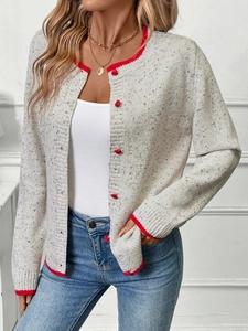 Close-up of knit cardigan featuring red heart buttons and contrast trim detailing