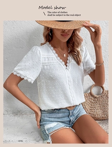 Detail of white V-neck textured top with delicate lace trim on sleeves and neckline
