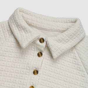 Detail shot of waffle texture cream sweatshirt with collar and brown buttons
