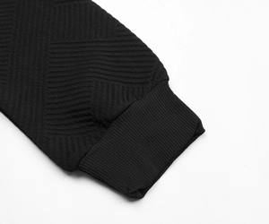 Close-up of black sweatshirt cuff with ribbed trim and geometric jacquard texture
