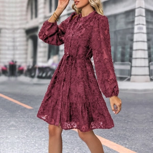Detail of burgundy lace dress featuring tiered skirts and textured eyelash fabric