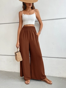 Detail of high-waist elastic waistband on brown wide-leg trousers with vertical texture