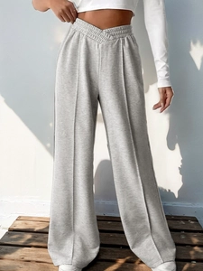 Detail view of light grey wide-leg joggers with unique V-shaped cross waist and vertical seams