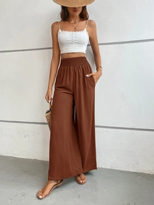 Detail of high-waisted brown wide-leg trousers with elastic pleated waist and soft drape