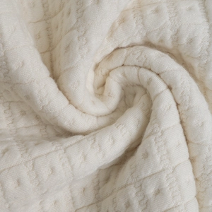 Detailed texture of off-white waffle knit fabric with diamond pattern and dot details