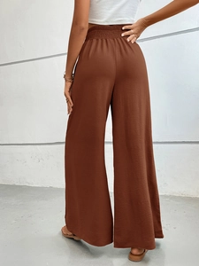 Rear view of high waist loose brown wide leg trousers with textured elastic waistband