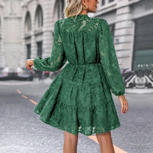 Detail showing deep green layered ruffle dress with textured feather-like fabric