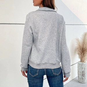 Detail of grey long-sleeve top featuring diamond quilted texture and lapel collar design